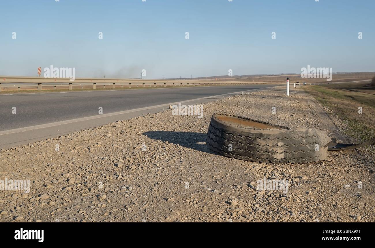 a torn car tire is lying on the side of the road Stock Photo