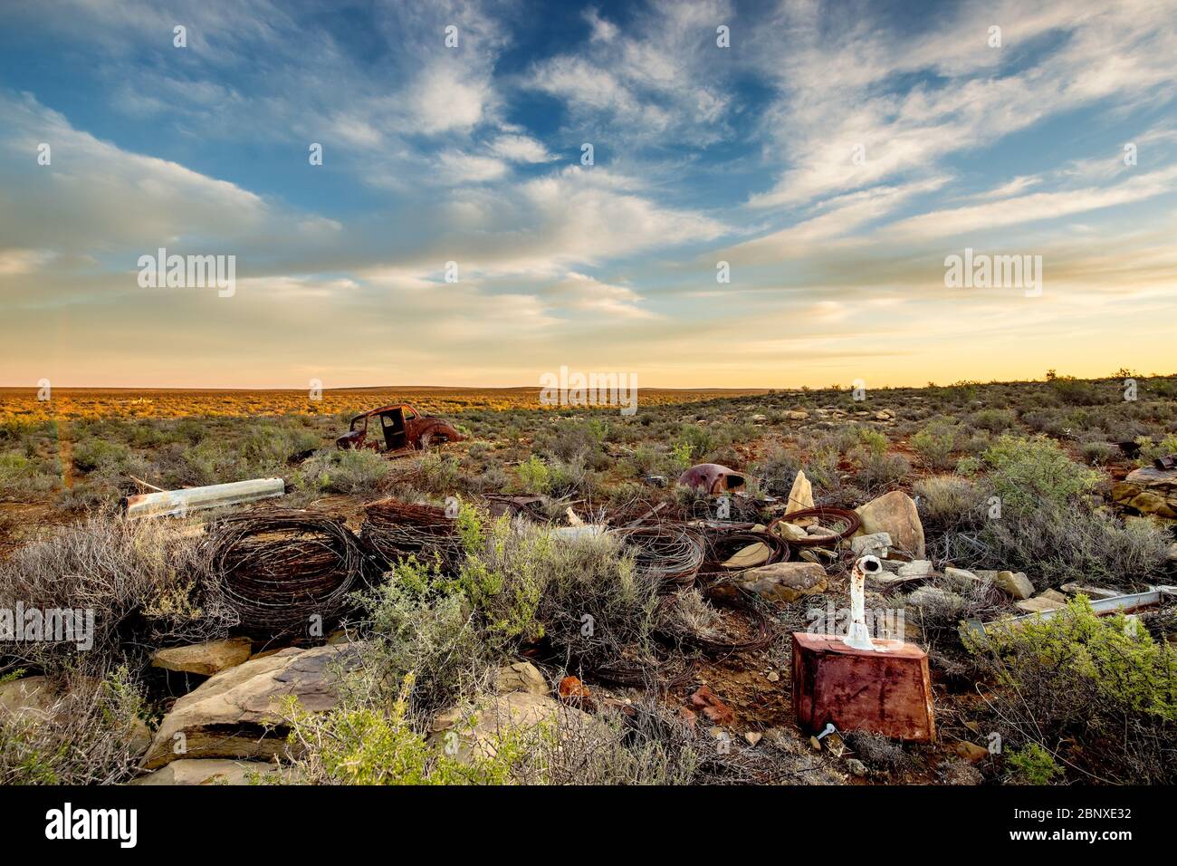 old car wreck under nice clouds in middle of nowhere Stock Photo
