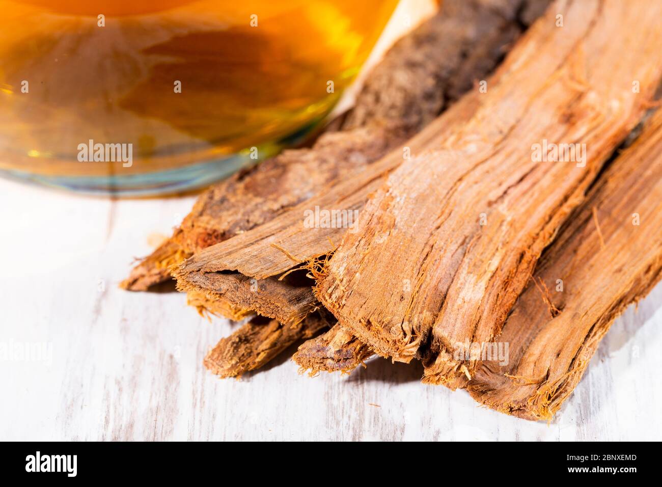 Tea and bark of cat's claw plant on wooden background, uncaria