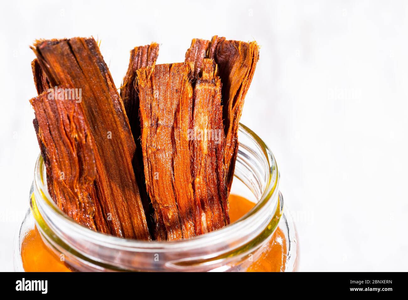 Tea and bark of cat's claw plant on wooden background, uncaria
