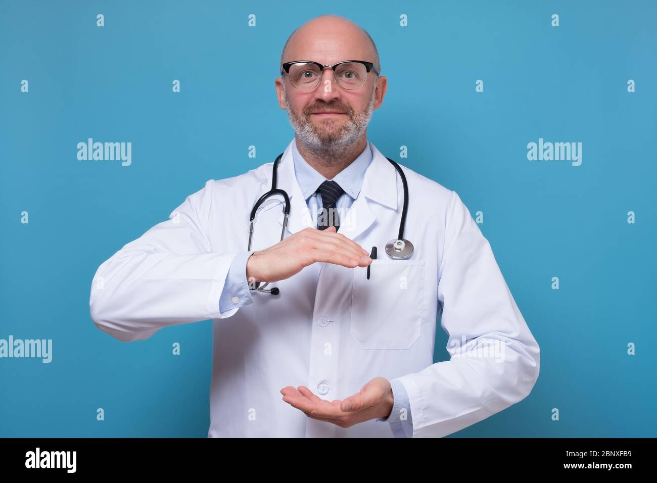 Handsome mature doctor holding something big between hands with copyspace Stock Photo