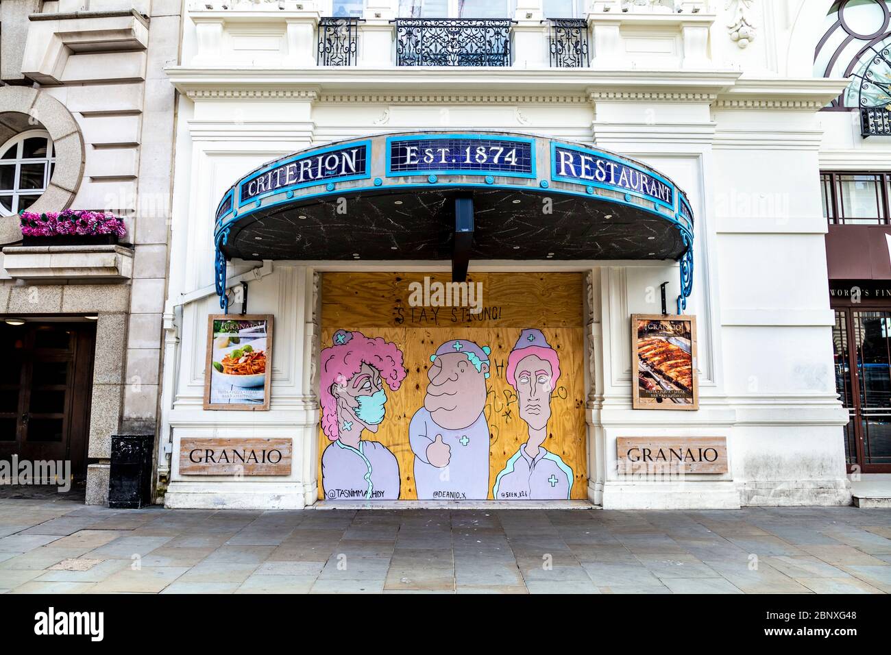 16 May 2020 London, UK - Boarded up Granaio Piccadilly restaurant with artwork of NHS nurses and doctors painted over the boards during the Coronavirus pandemic lockdown with a 'Stay Strong' message Stock Photo