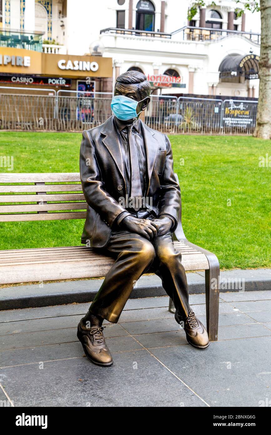 16 May 2020 London, UK - Statue of Mr Bean sitting on a bench wearing a protective face mask in Leicester Square during the coronavirus pandemic lockdown Stock Photo