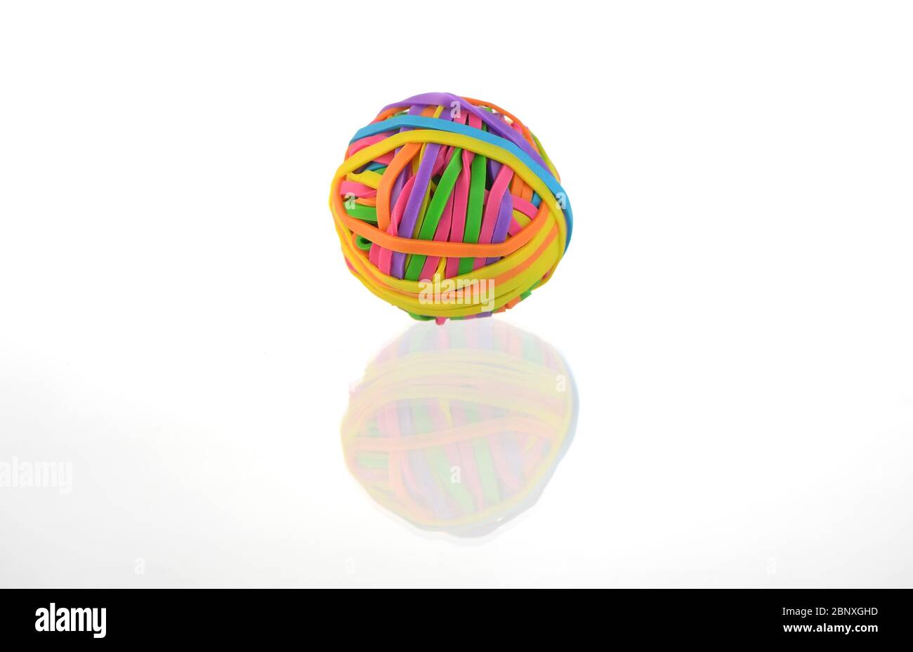 A colourful ball of elastic bands isolated against a white background with a reflection. Stock Photo