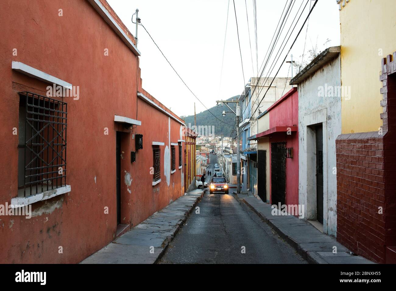 Narrow, hilly street with colourful residential houses in central Quetzaltenango (Xela), Guatemala. Mar 2019 Stock Photo