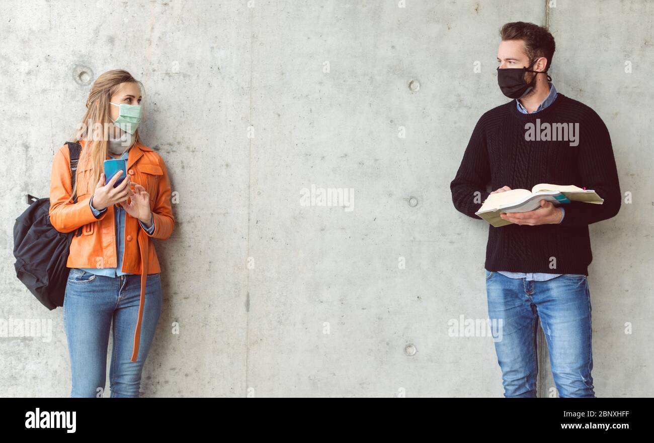 Two students standing in social distance wearing face mask Stock Photo