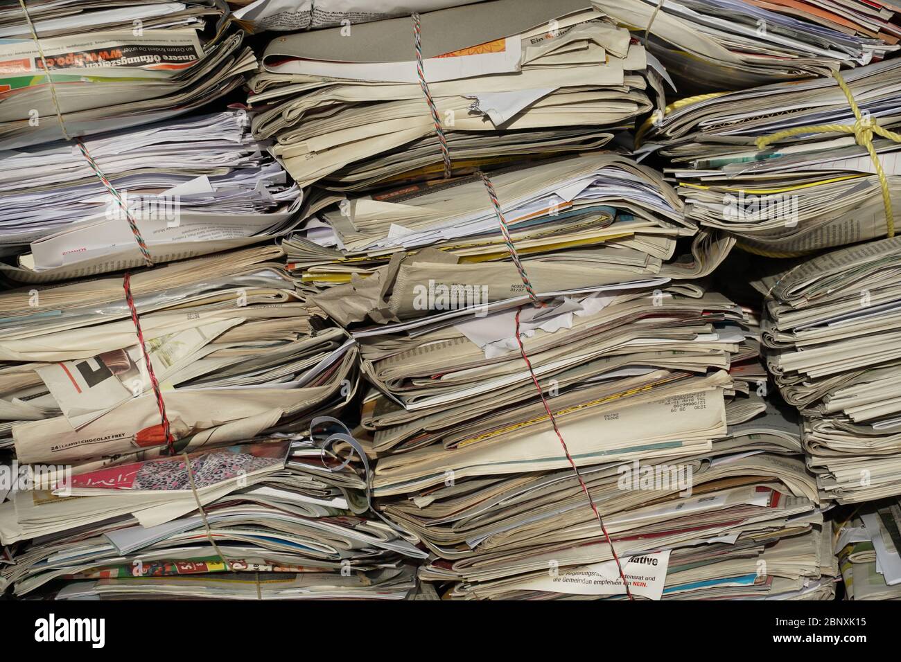 bundles of old newspapers stacked for recycling cleating a background, filling the whole space of the photo, it is friendly to environment to collect Stock Photo