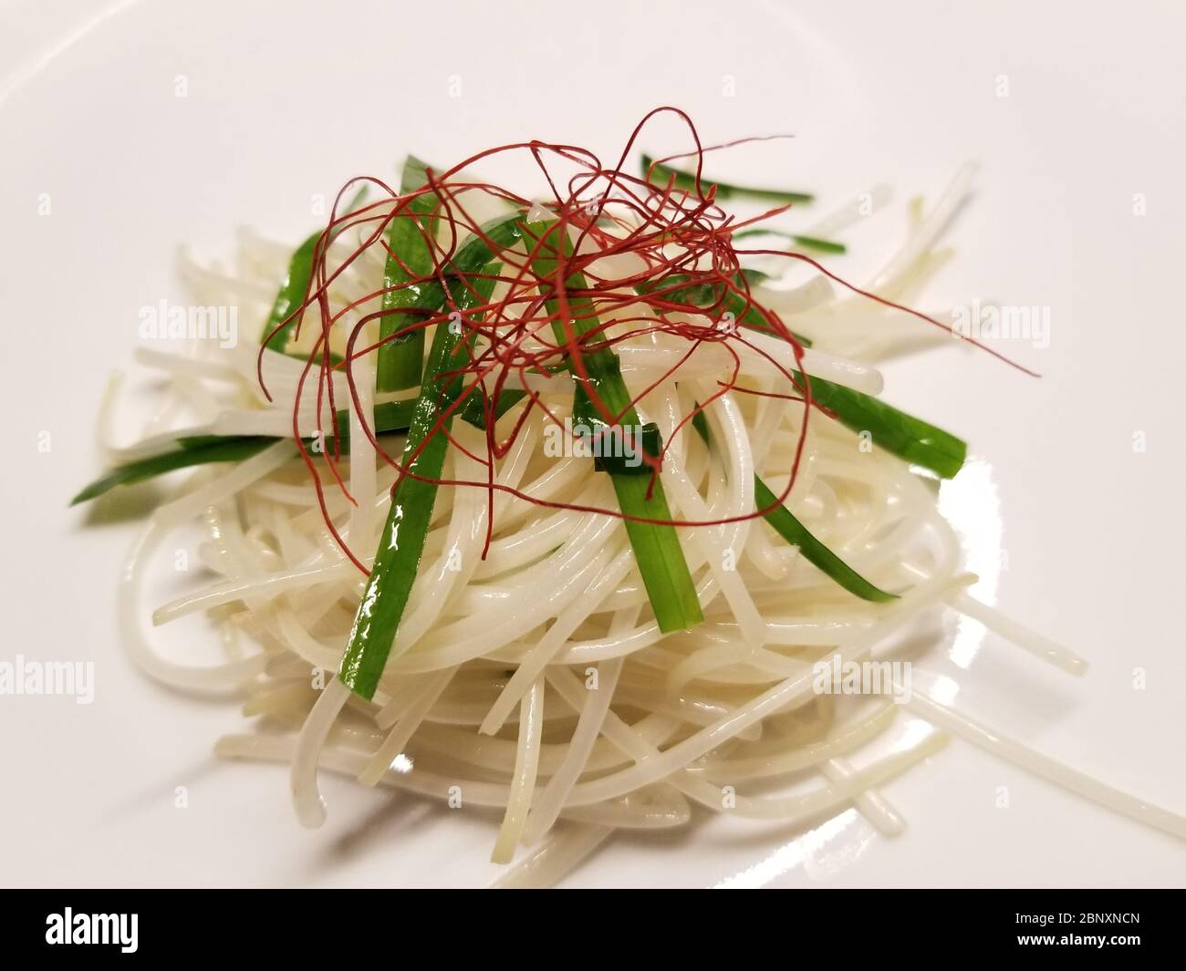 Bean sprout salad consisting of stir fried bean sprouts, chives, and stringy red pepper, on a white background Stock Photo