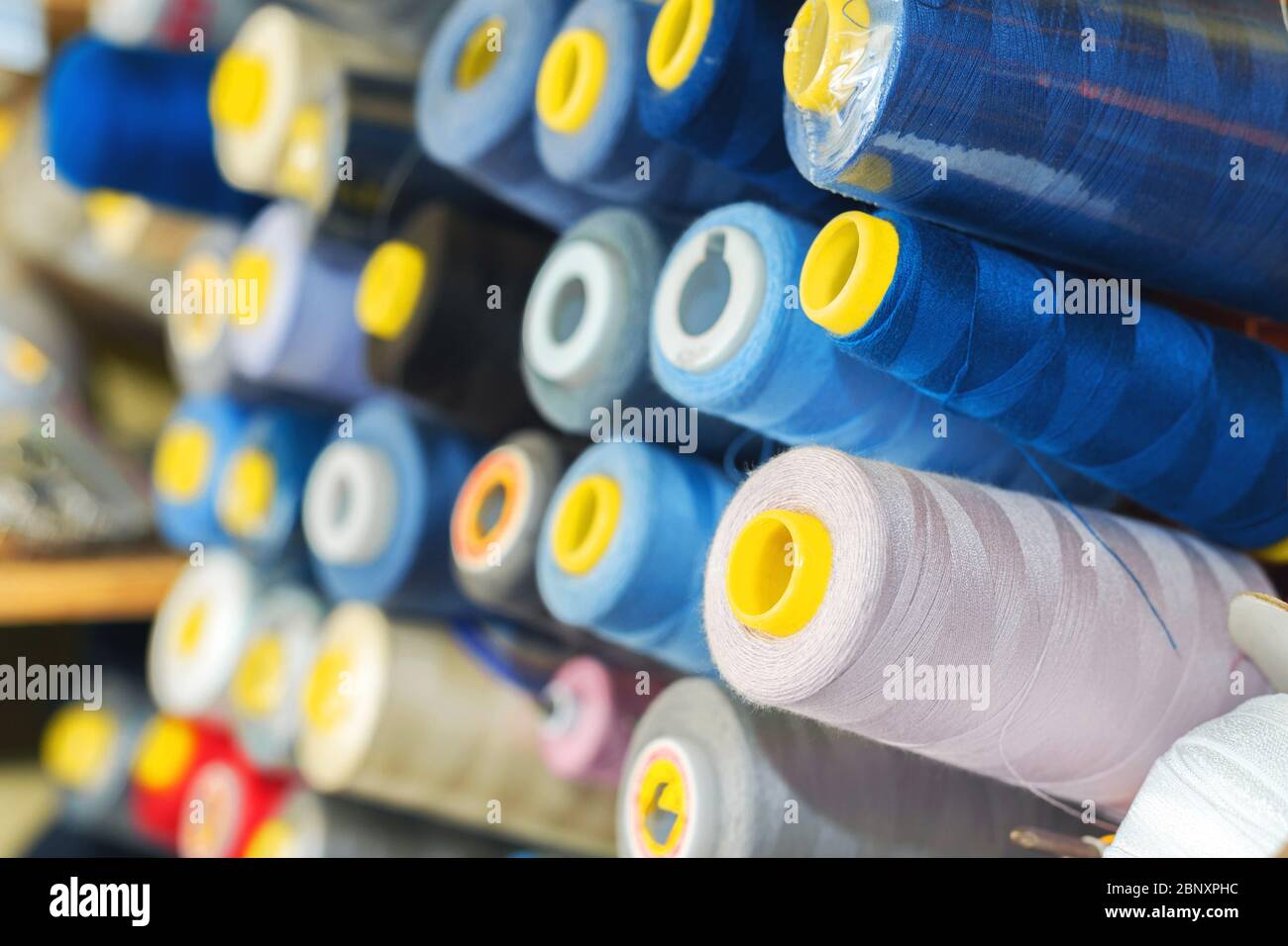 Colored thread on bobbins in a sewing workshop. Garment industry concept Stock Photo