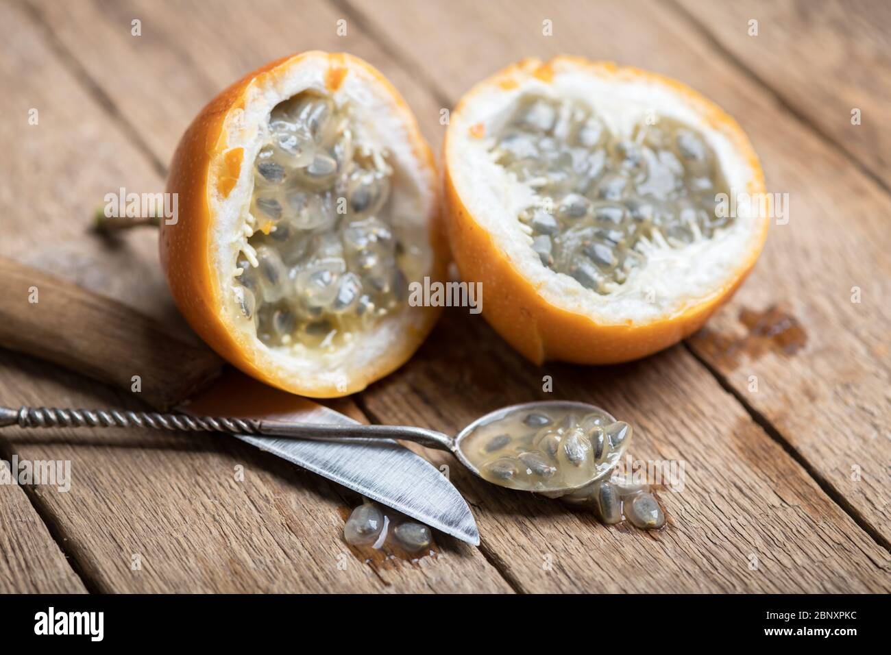 Slised passion fruit with knife and spoon on rusty wooden background. Food photography Stock Photo