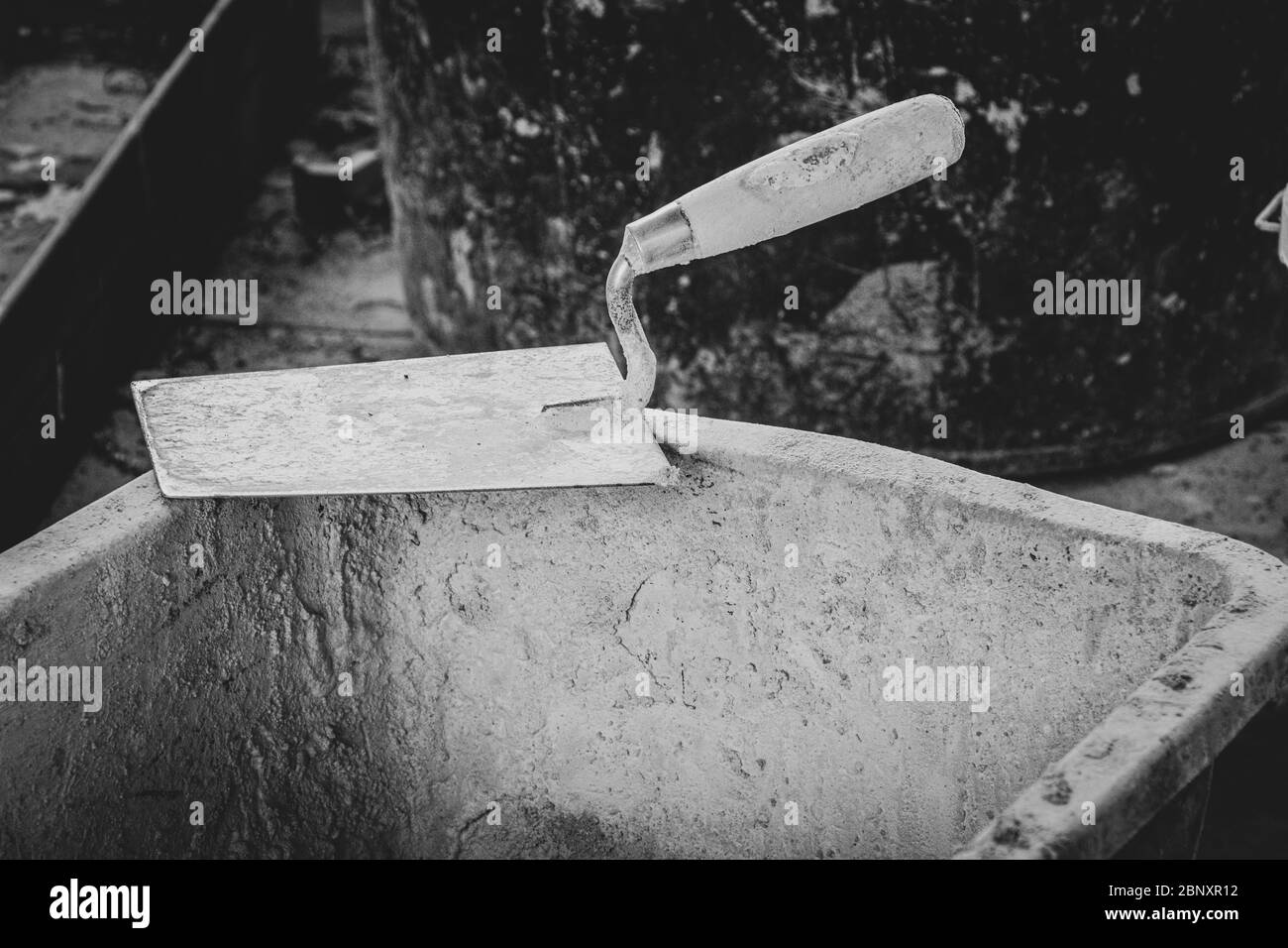 a trowel lies on the edge of a mortar box on a building site Stock Photo