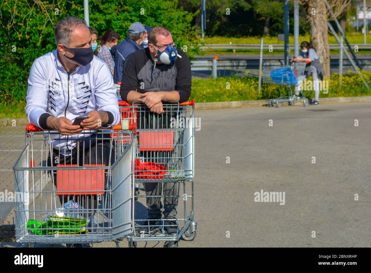 Toscana, Italy 04/08/20 - Closeup of group of patient italian white men and women wearing COVID-19 protection masks. Line of people with shopping cart Stock Photo