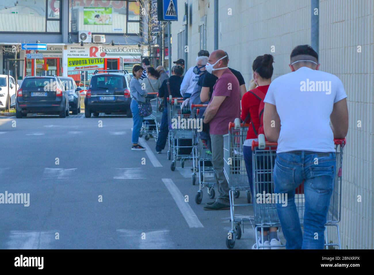 Tuscany, Italy 04/08/20 - Long line of people waiting with shopping carts to buy groceries in lockdown. Corona virus pandemic and social distancing Stock Photo