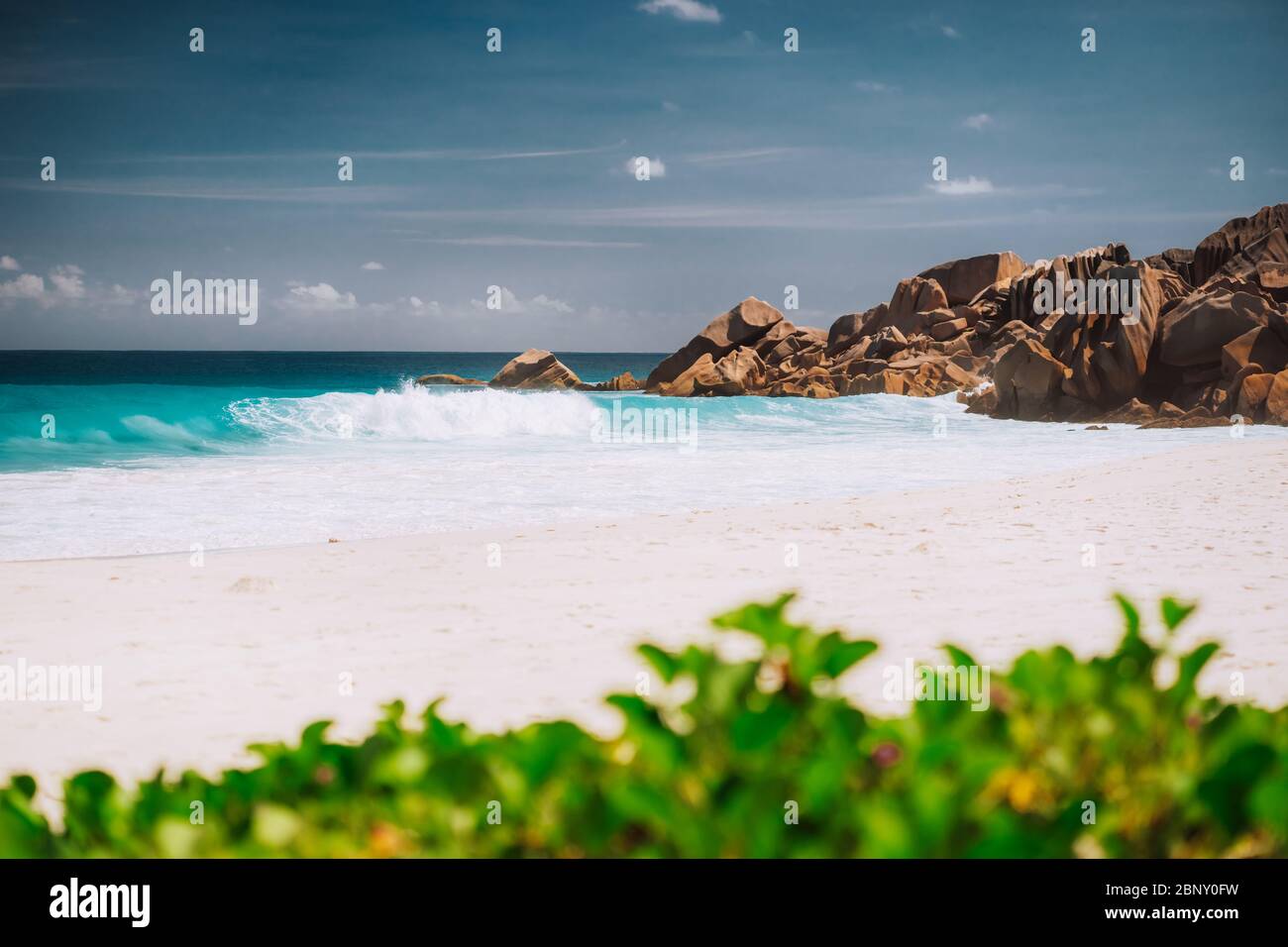 Ocean foamy waves and white sand beach at Petite Anse, La Digue in Seychelles Stock Photo