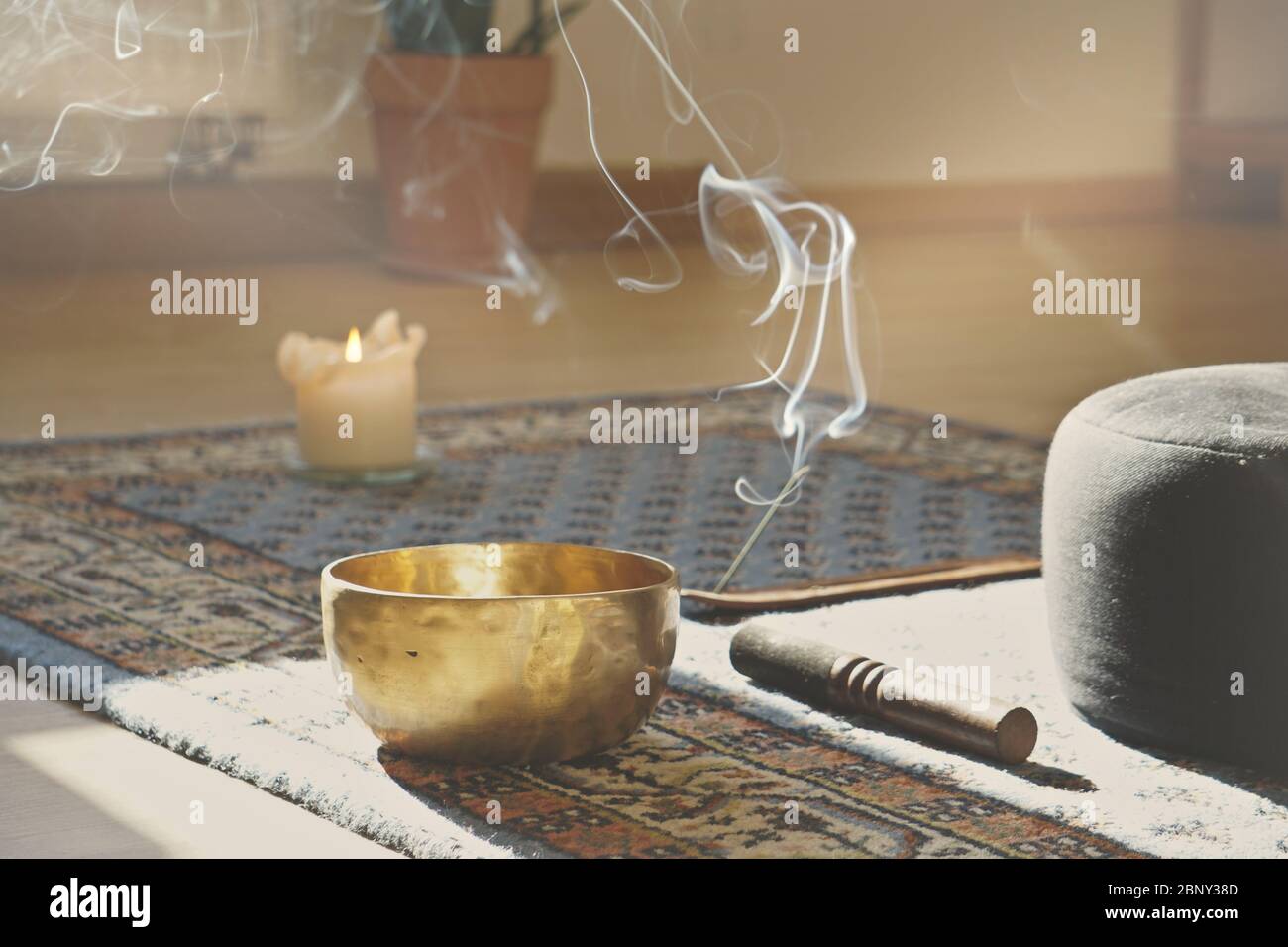 meditation room with singing bowl, incense stick, smoke, pillow and candle Stock Photo