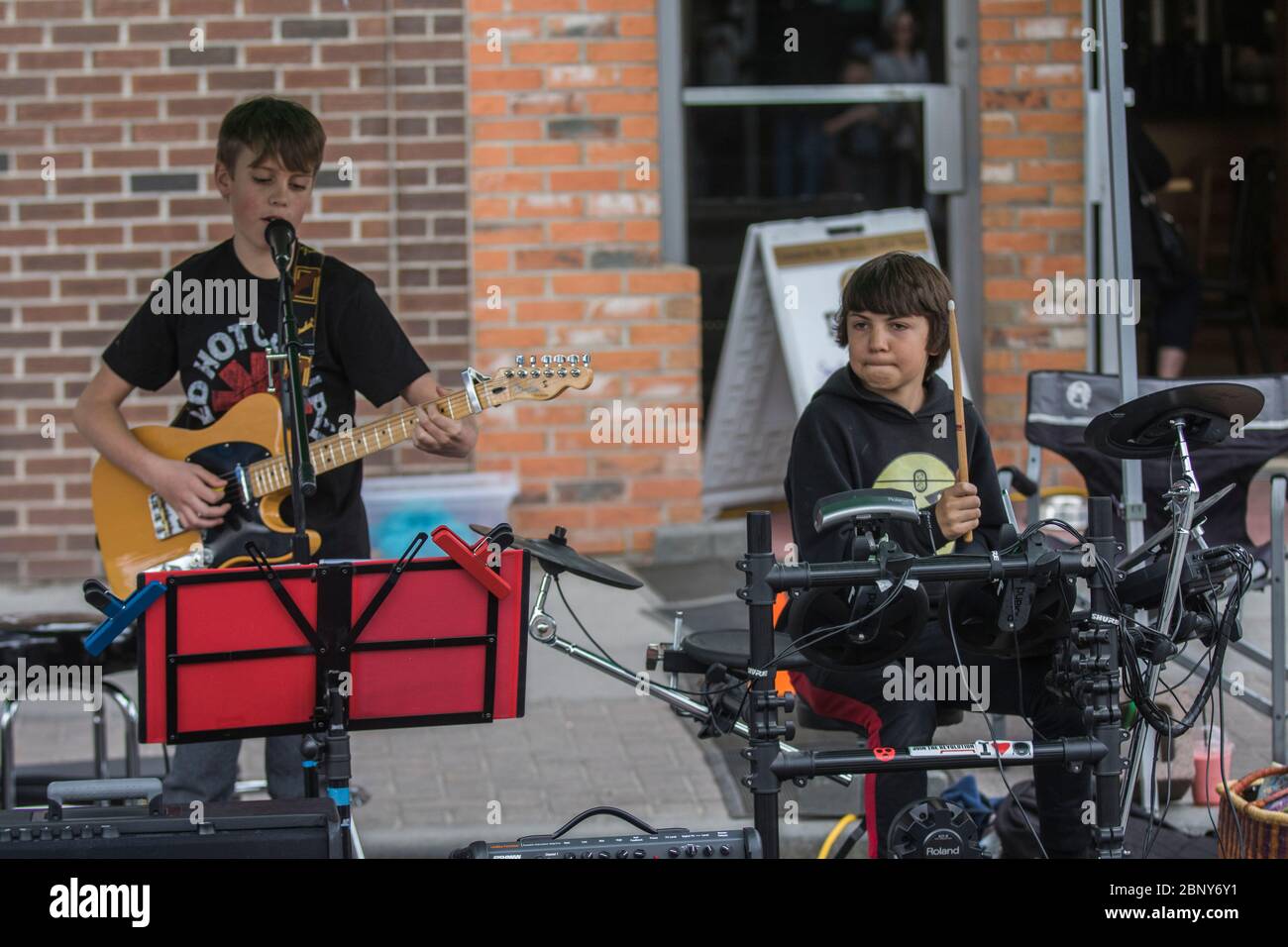 Two young boys, drummer and guitar player, performing at outdoor