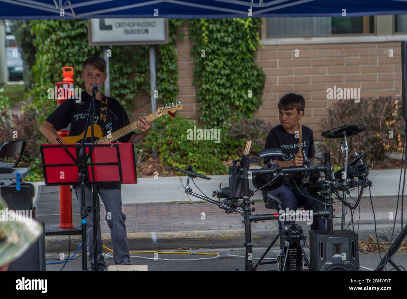 Two young boys, drummer and guitar player, performing at outdoor