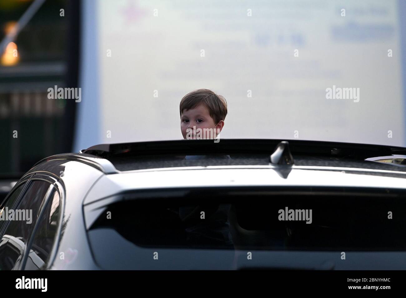 New York City, USA. 16th May, 2020. A young boy pops his head out of a vehicle's sunroof at Bel Aire Diner ‘drive-in theatre before the start of the movie, in the Astoria neighborhood of Queens, New York, NY, May 16, 2020. With restaurants limited to take-out under Coronavirus city rules, Bel Aire Diner allows motorist who reserved spots in their parking lot to order from the diner as they watch a movie. (Anthony Behar/Sipa USA) Credit: Sipa USA/Alamy Live News Stock Photo