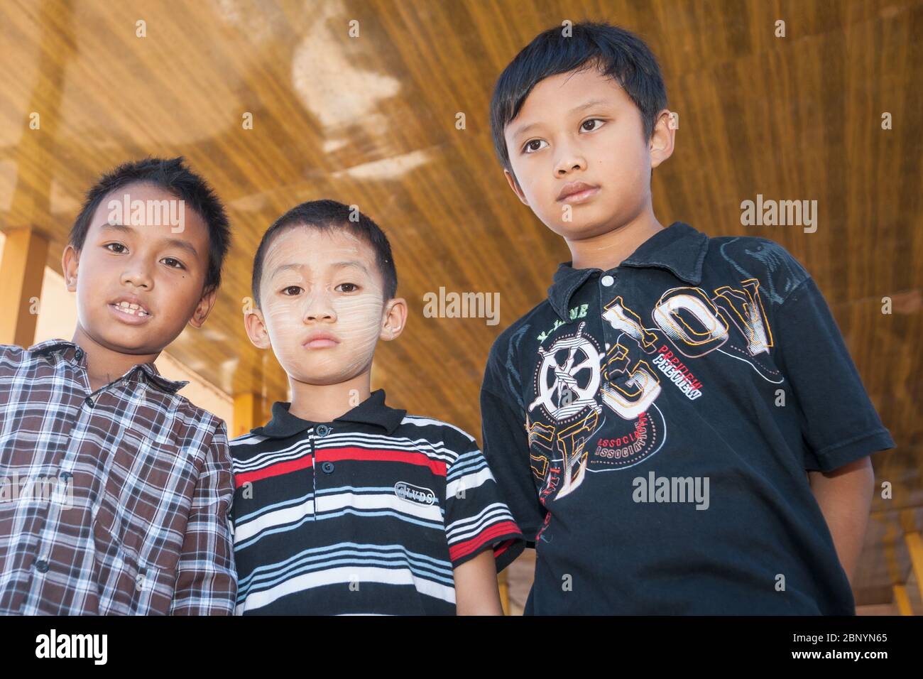 Inle Lake Myanmar - November 3 2013; Three boys standing looking down with different looks and one with traditional Burmese thanaka on his face. Stock Photo