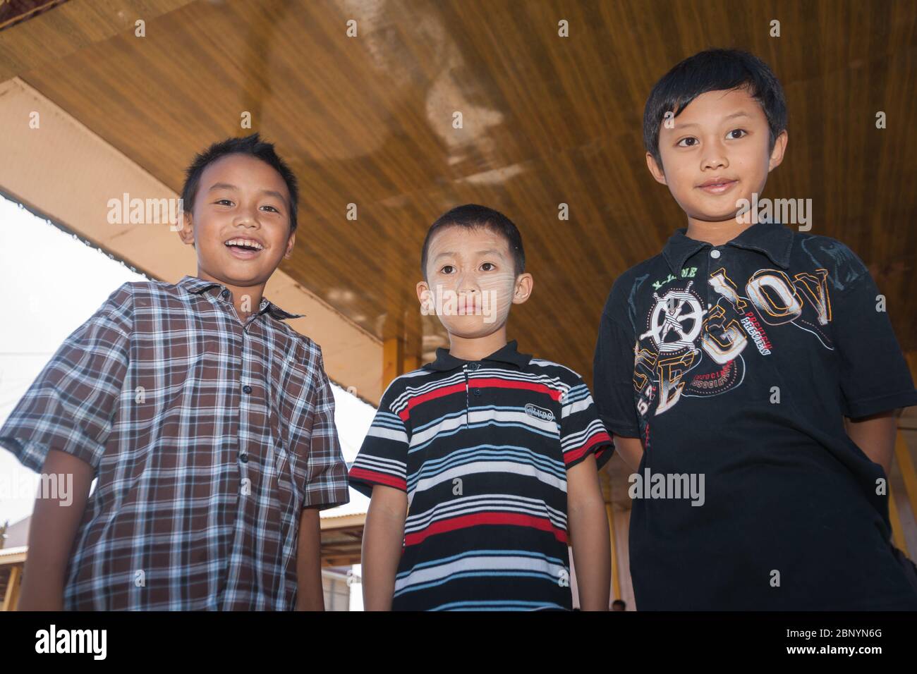 Inle Lake Myanmar - November 3 2013; Three boys standing looking down with different looks and one with traditional Burmese thanaka on his face. Stock Photo