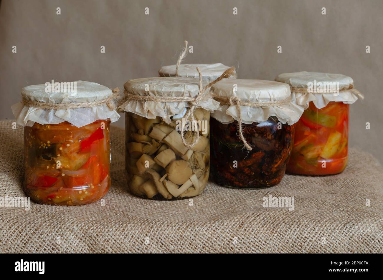 Homemade canned food. Canned food in glass jars. Various canned food on burlap. Preservation and storage of crops. Close-up. Stock Photo