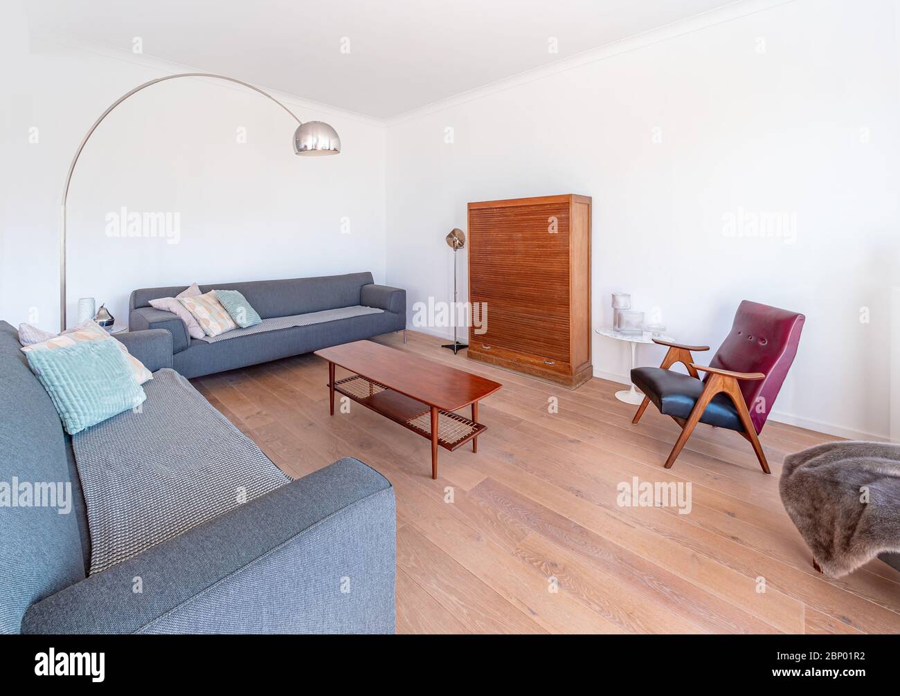 Minimal stylish bright living room with wood floor, big sofas, wooden table, modern lamp, big windows and retro furnitures. Spacious Scandinavian styl Stock Photo