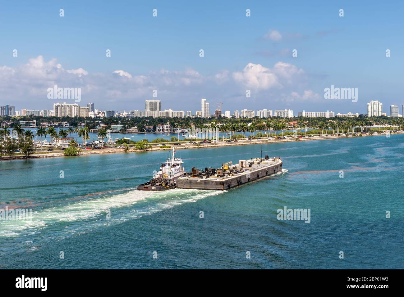 Miami, FL, United States - April 27, 2019: Tug boats helping the platform to navigate in Miami port. The busy Miami Main Channel water traffic in Miam Stock Photo