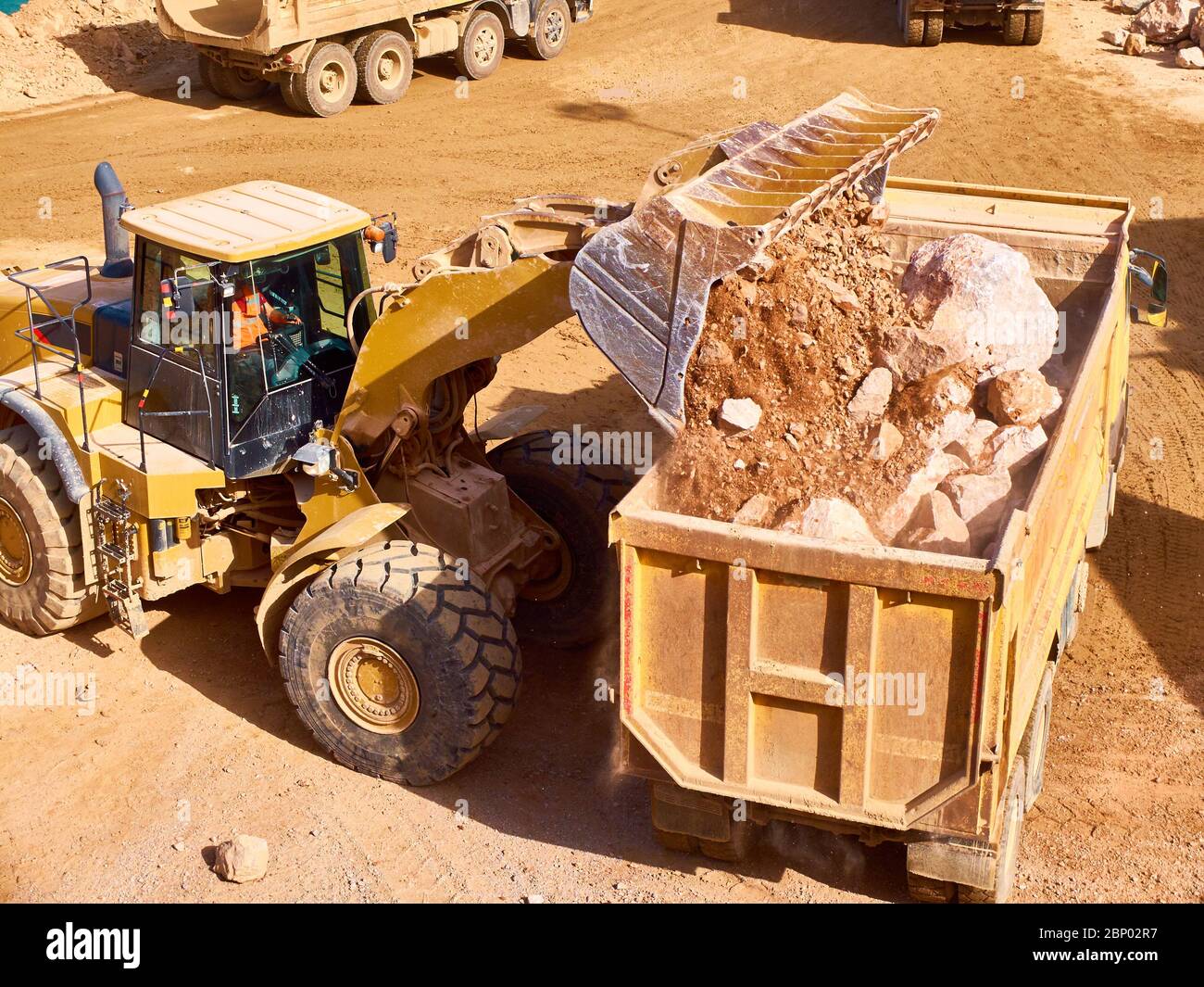 front loader loads rock into a dump truck Stock Photo - Alamy