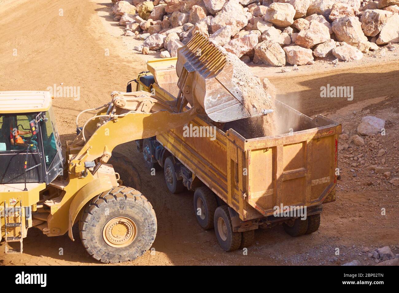 front loader loads rock into a dump truck Stock Photo - Alamy