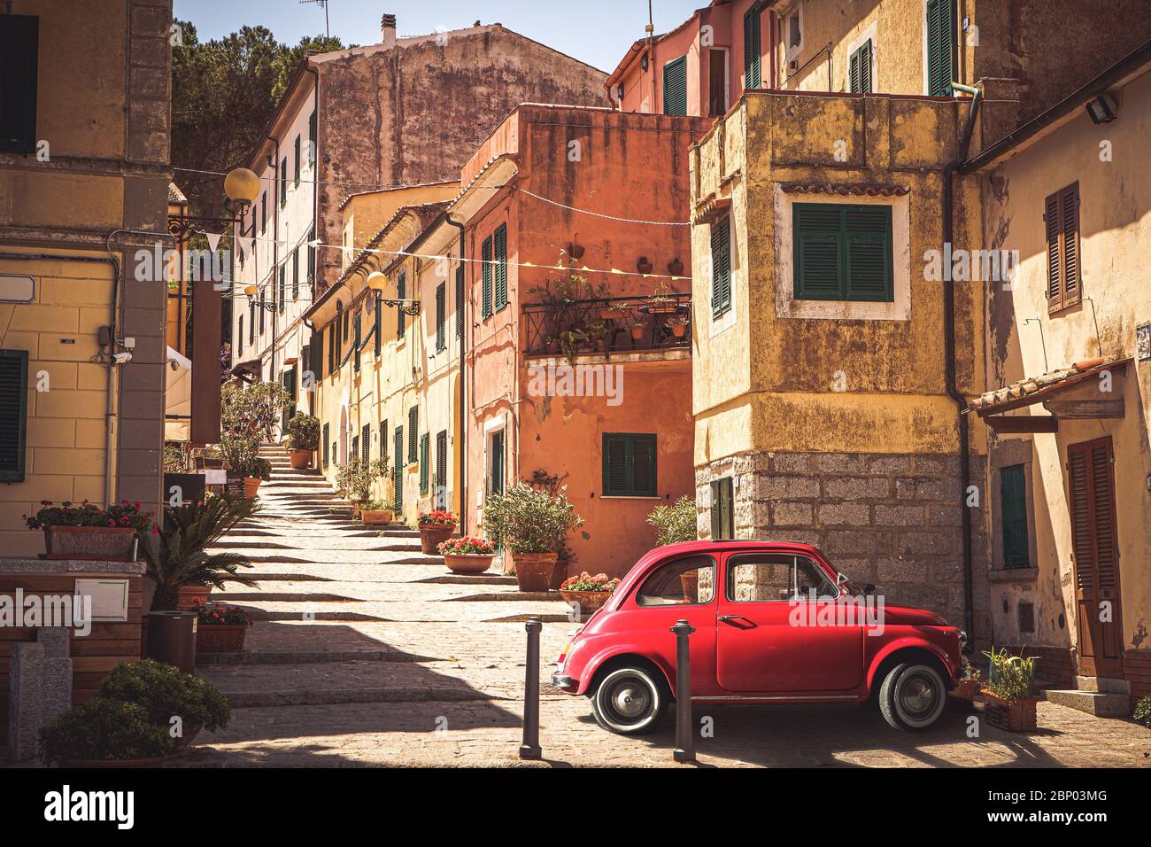 Old red vintage car italian scene in the historic center of small village in Italy. Elba Island, Marina di Campo city. Retro vintage setting, nostalgi Stock Photo