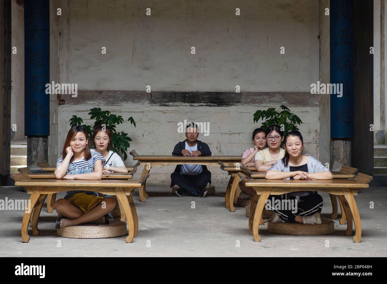 Although Hongcun village is a UNESCO World Heritage Site, it is also a residential town. Here, five schoolgirls and their male instructor sit behind d Stock Photo