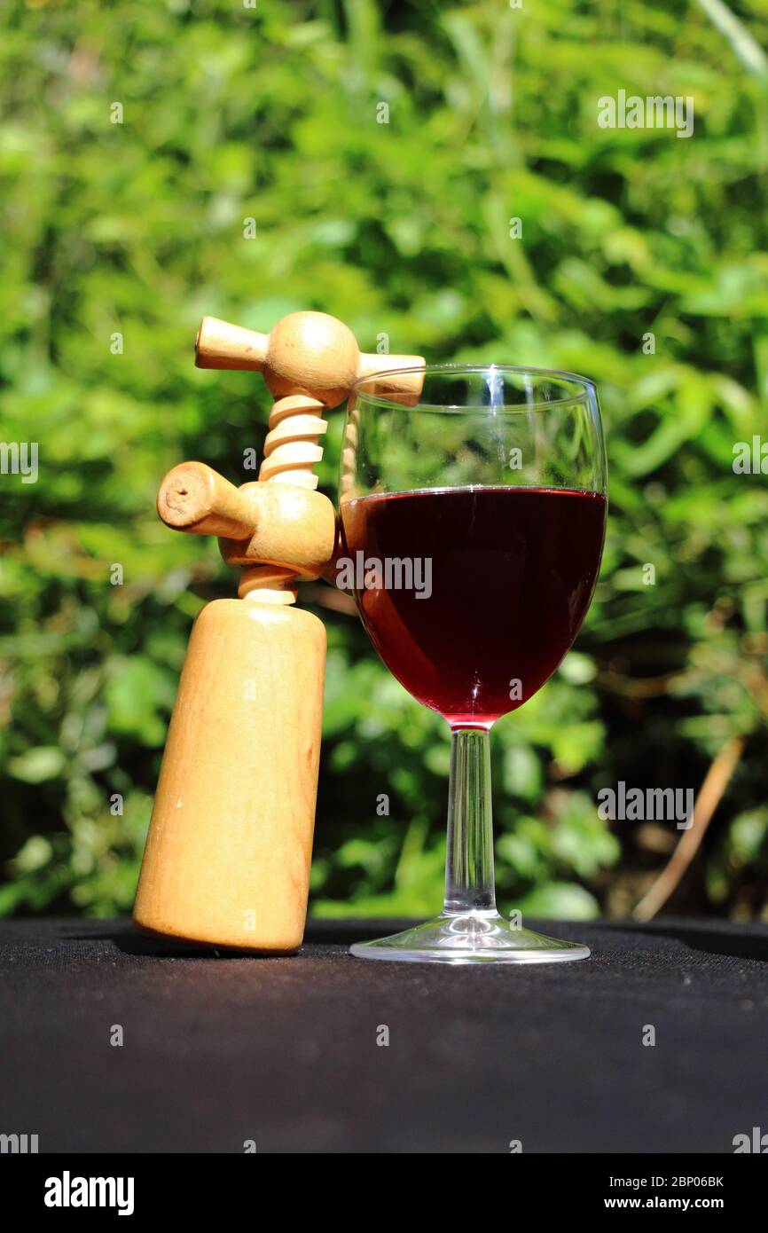A glass of red wine in a natural environment with a corkscrew Stock Photo