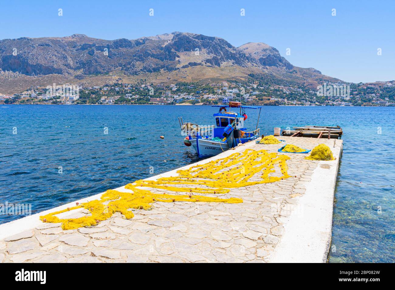 Fishing boat and yellow nets out to dry on the jetty of the small port town of Telendos Island, Kalymnos, Dodecanese, Greece Stock Photo