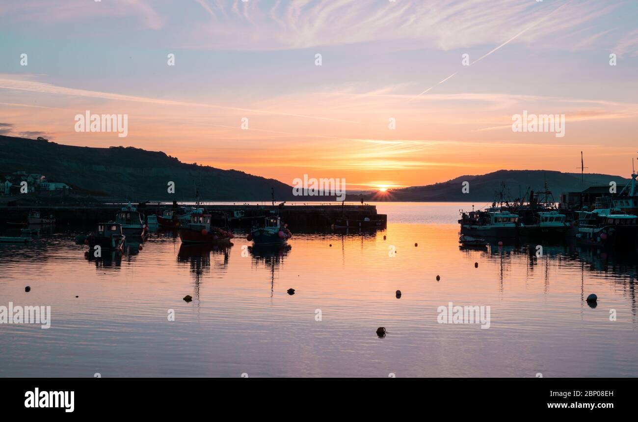 Lyme Regis, Dorset, UK. 17th May, 2020. UK Weather: The sun rises over the Cobb Harbour at the start of another warm and sunny day at the seaside town of Lyme Regis. Credit: Celia McMahon/Alamy Live News Stock Photo