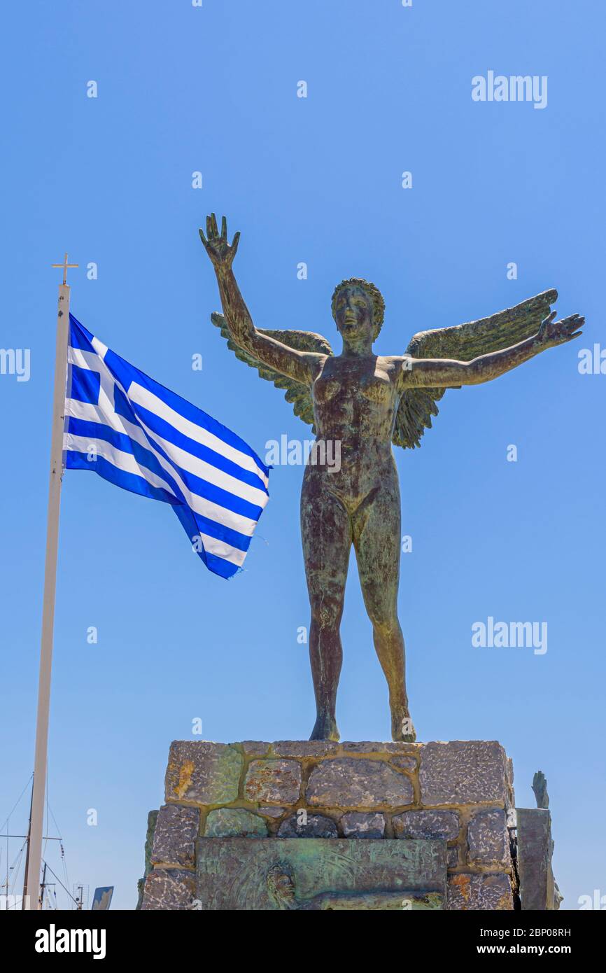Winged Nike statue next to the Greek flag in Pothia Town, Kalymnos, Dodecanese, Greece Stock Photo