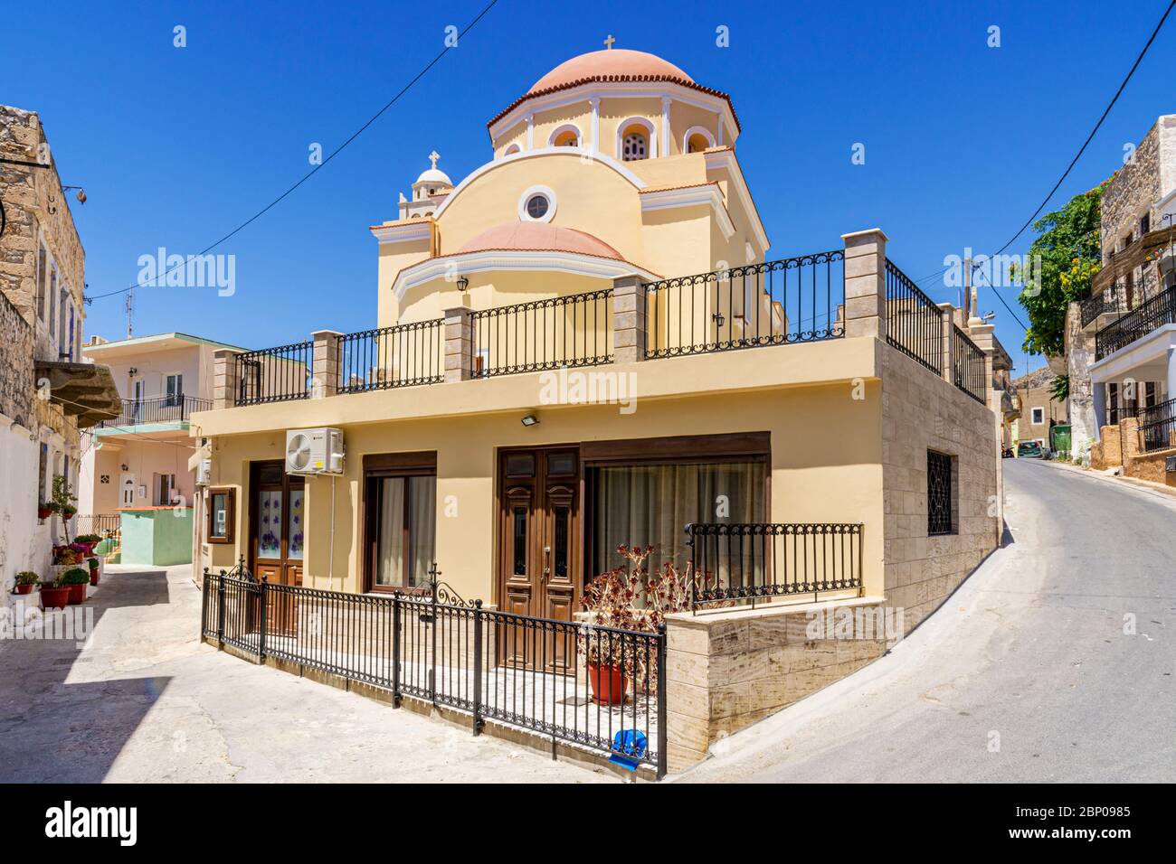 Greek Orthodox church and house underneath in the back streets of Pothia, Kalymnos, Dodecanese, Greece Stock Photo