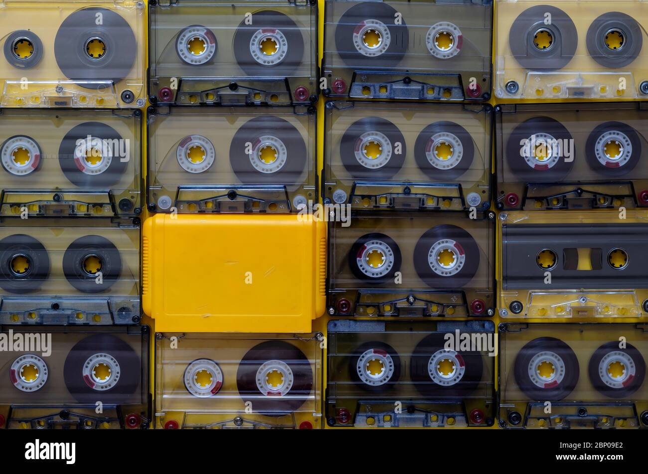 Creative background from audio cassettes and a yellow game cartridge. A set of random audio cassettes with 1990s music recordings full frame. Entertai Stock Photo
