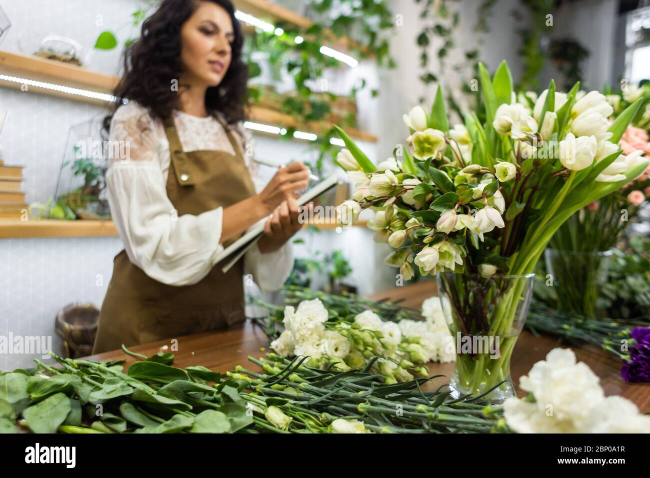 Attractive young woman florist is working in a flower shop Stock Photo ...