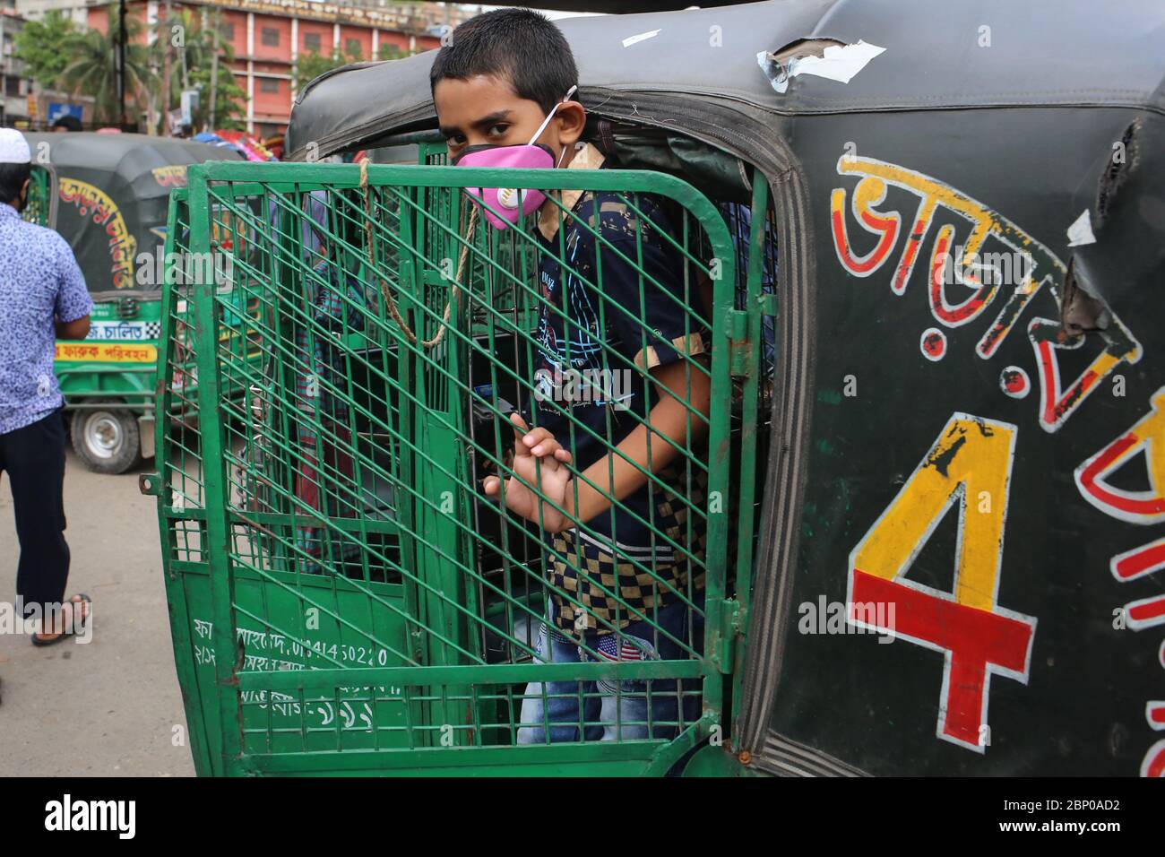 Dhaka, Dhaka, Bangladesh. 16th May, 2020. A kid who is wearing facemask to prevent covd - 19 from being spread is standing in a CNG auto riksha before leaving.Mass transportation is on hault for 52 days now to prevent the amid spread of novel coronavirus Credit: Md. Rakibul Hasan/ZUMA Wire/Alamy Live News Stock Photo