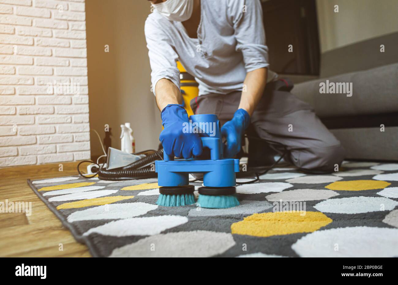 Dry cleaner's man employee removing dirt from carpet, vacuum clean with