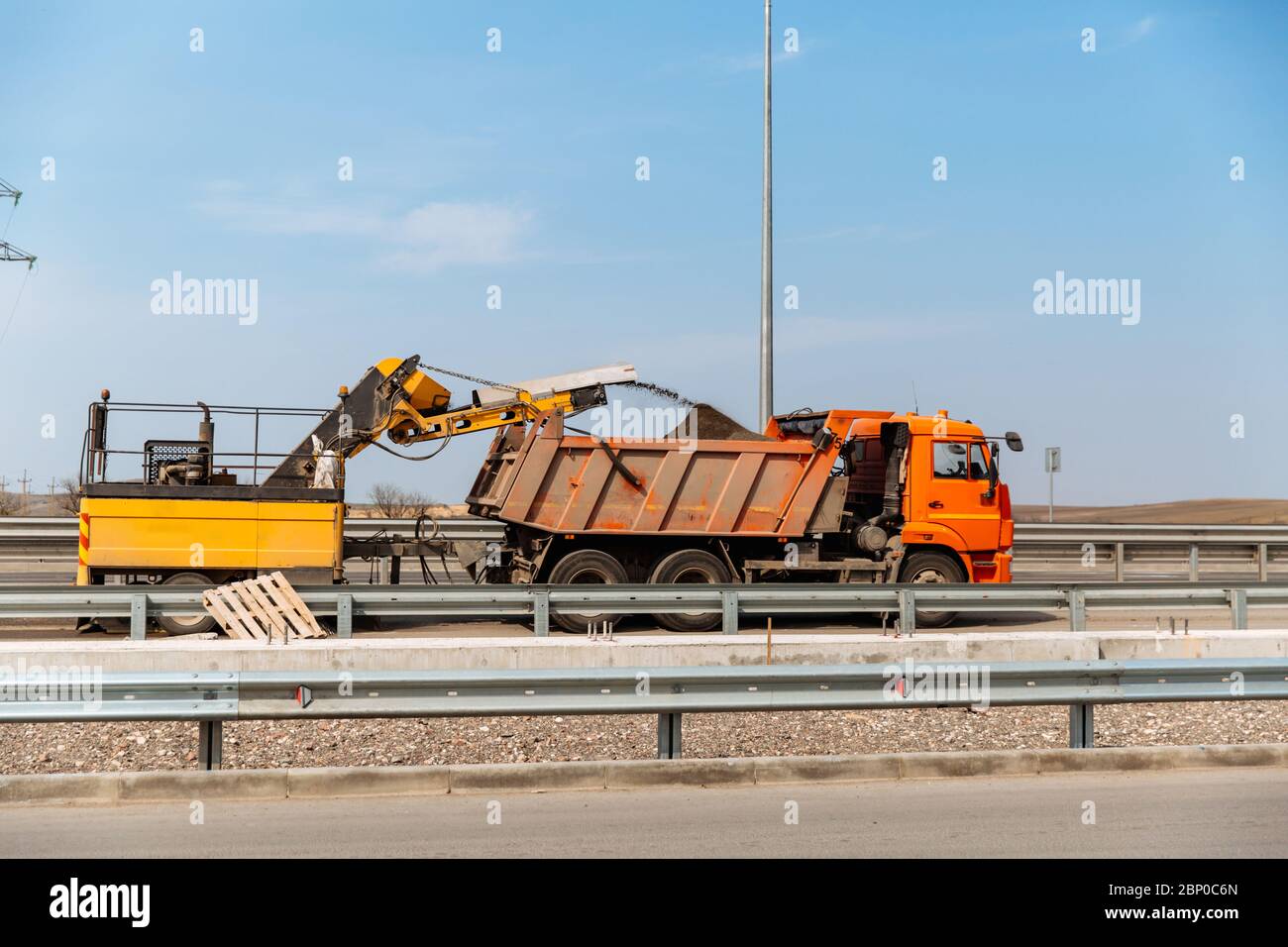 Road works. Recycled asphalt crumb is poured over the conveyor belt