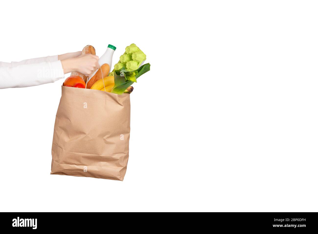 Food delivery or donation concept. Grocery store shoping. Female hands holds a paper bag filled with groceries such as fruits, vegetables, milk, yogur Stock Photo