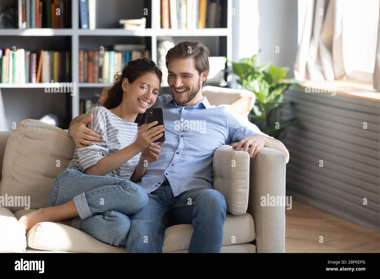 Happy young couple using smartphone at home Stock Photo