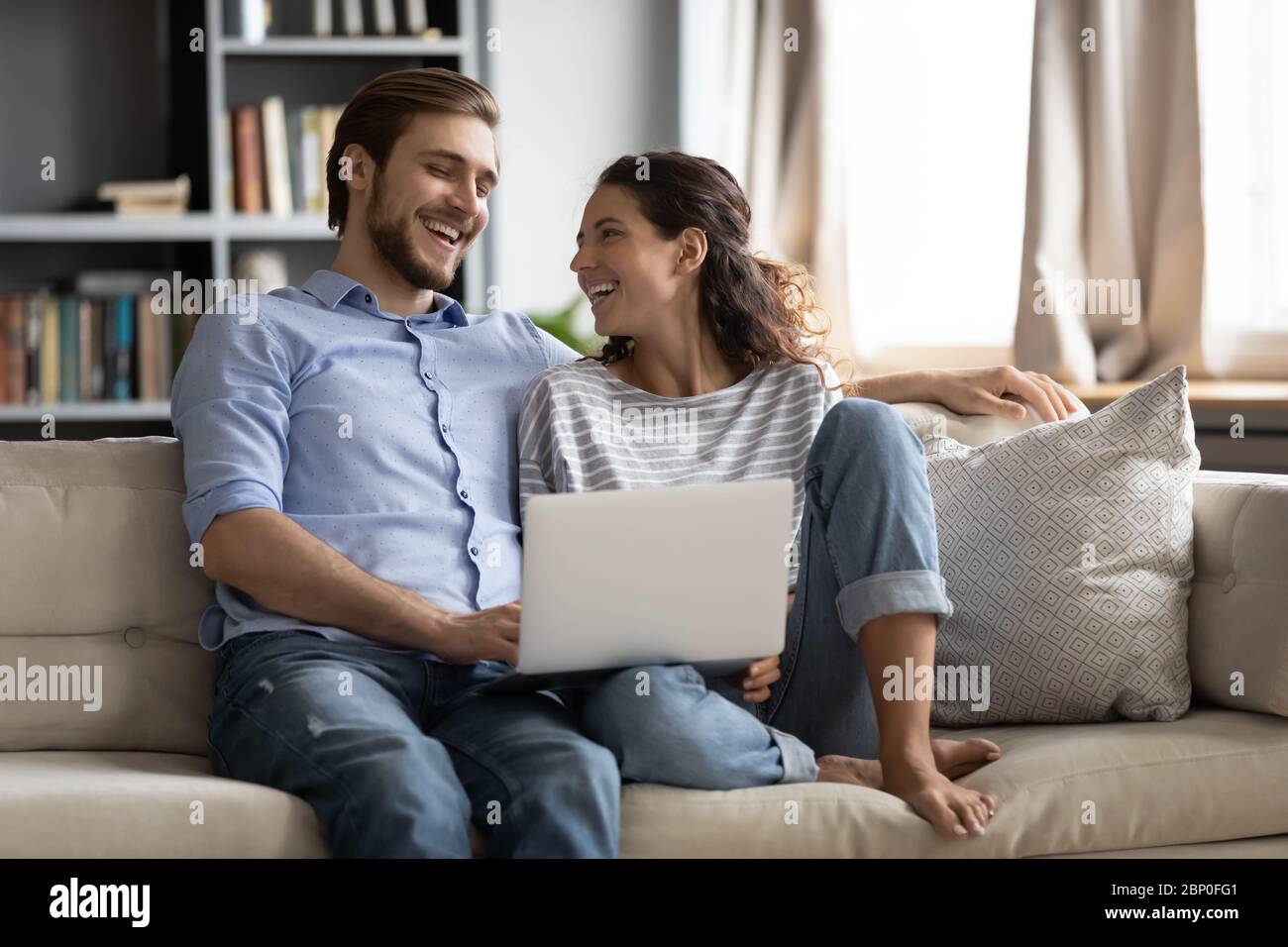 Happy couple relax on sofa using laptop together Stock Photo