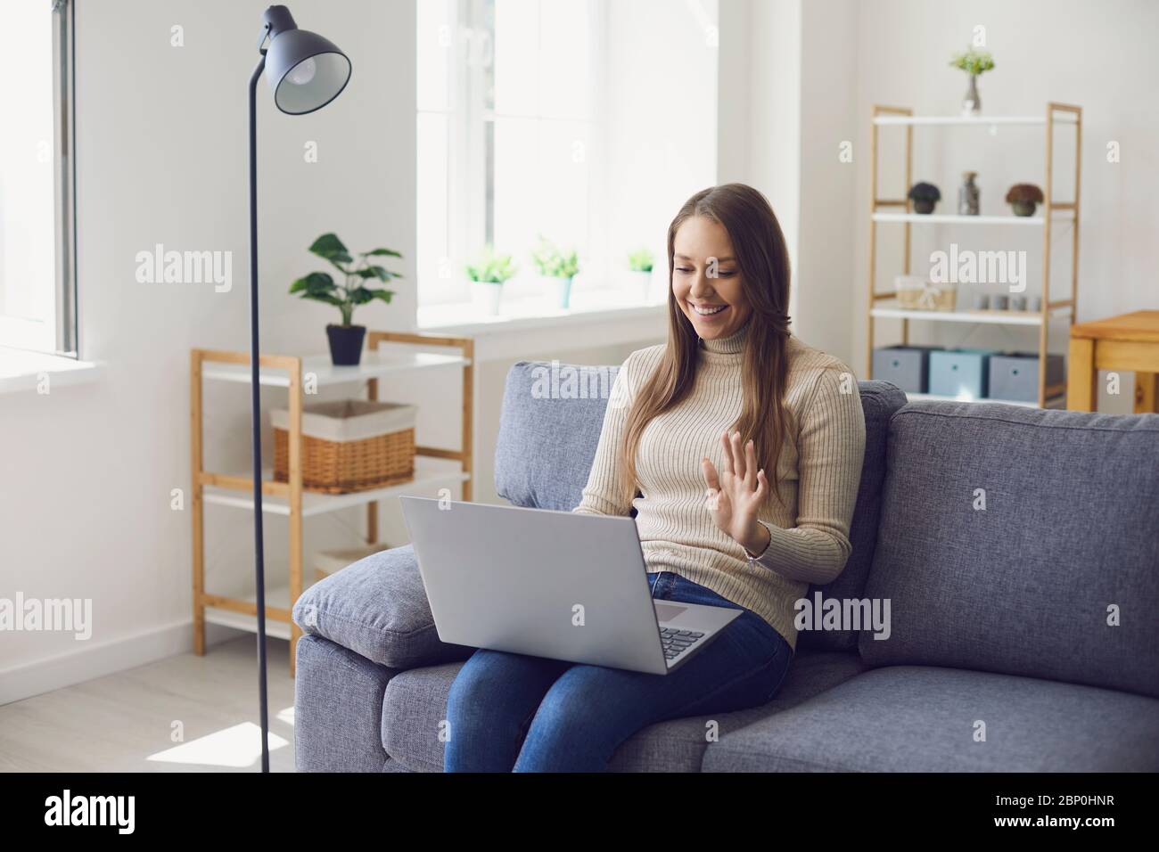 Online work at home. A woman works at a table in using a laptop she speaks with a partner through the video call chat application at home. Stock Photo