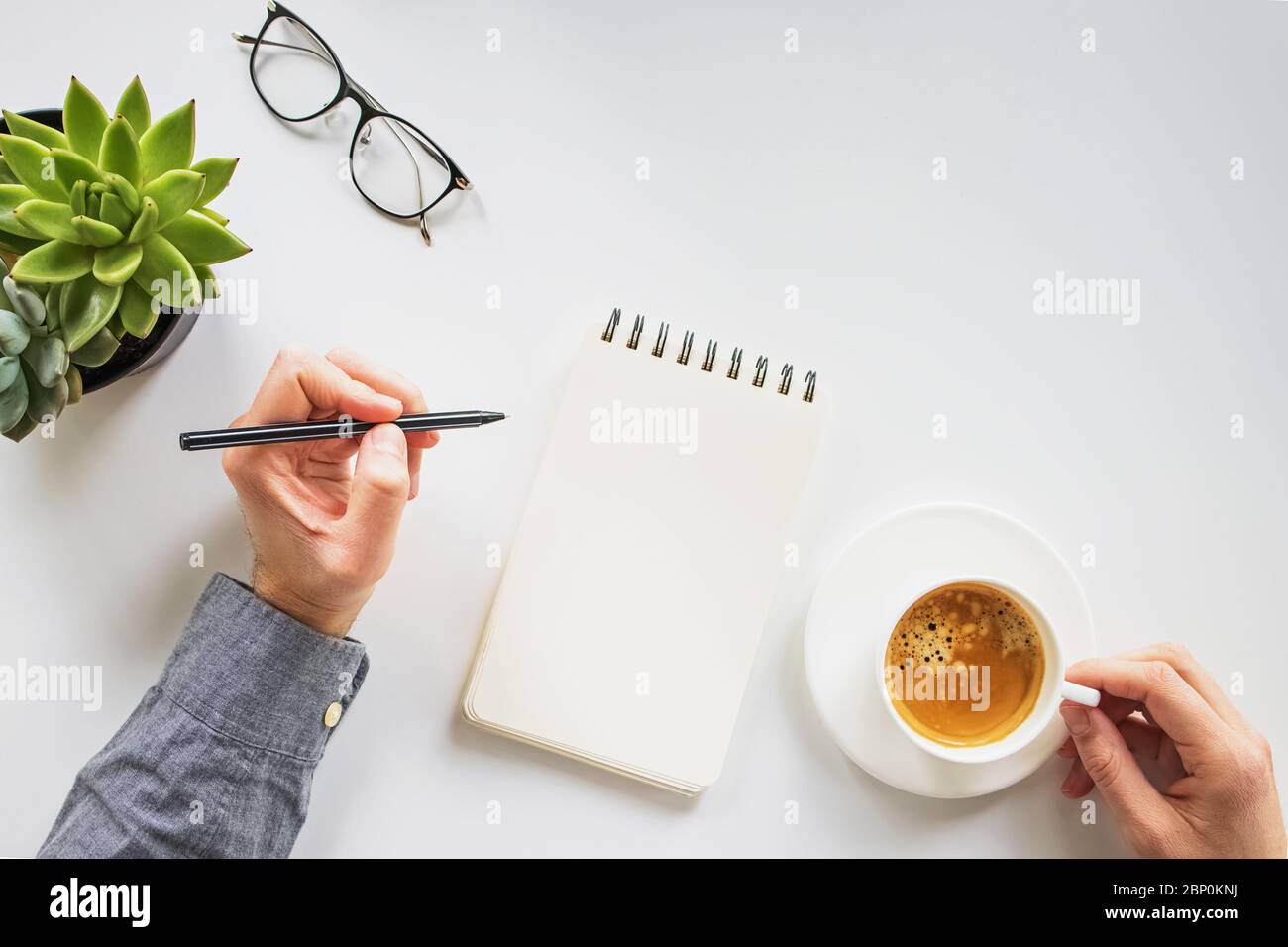 Man working writing in the notepad and drinking coffee Stock Photo