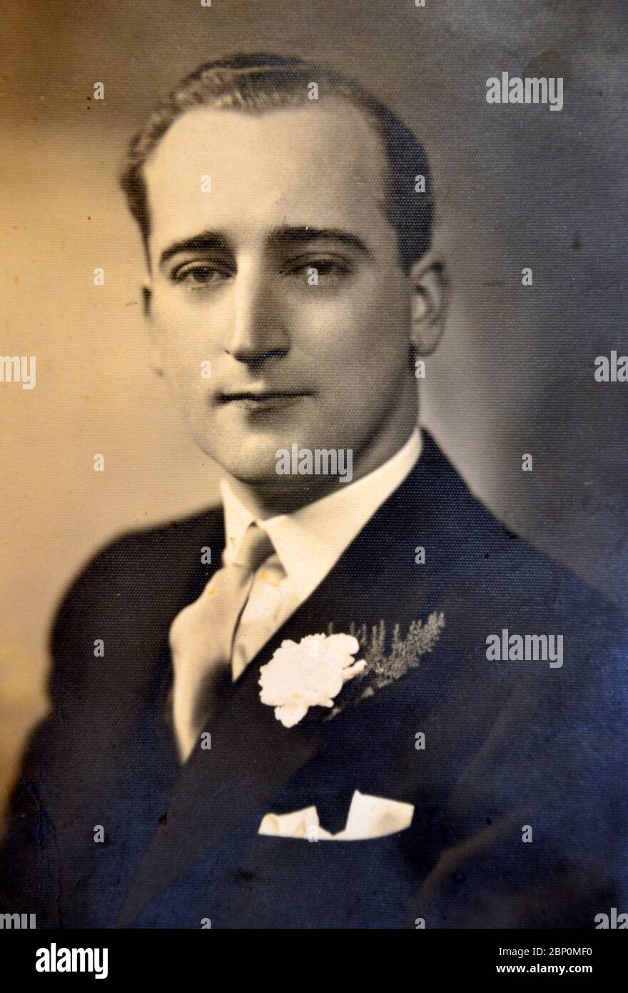 Archival studio photograph of a handsome Caucasian man, aged about 25, smartly dressed with a boutonnière in his lapel, on his wedding day in 1940. Stock Photo