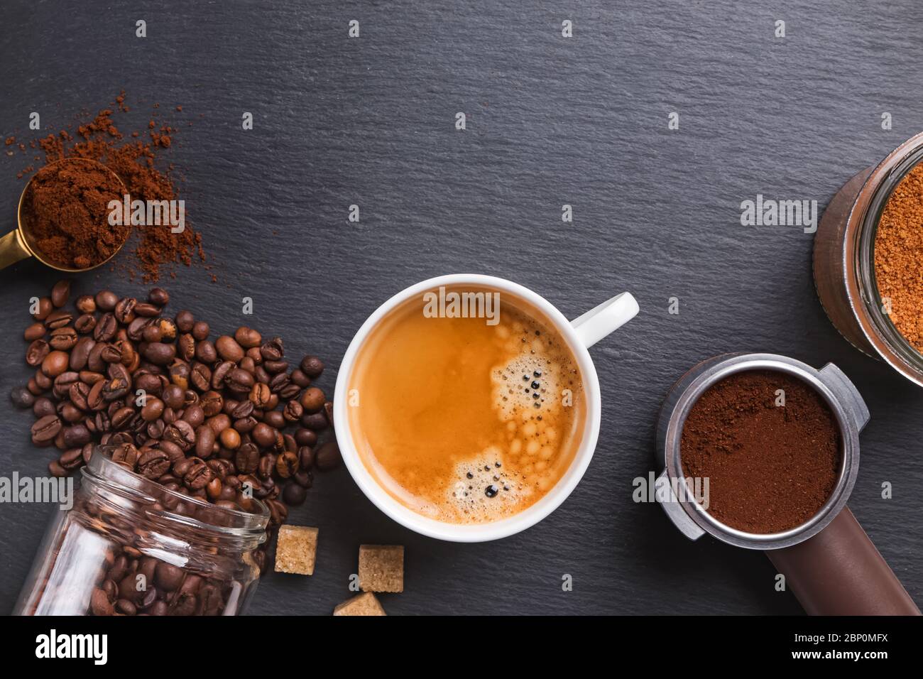 Top view of cup of Espresso, coffee beans, ground and sugar on black