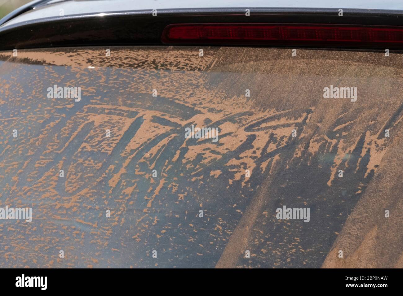 Rear window of a car covered with sand. Dutch sense means that the car