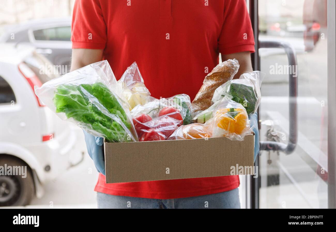 Delivery of products from supermarket during epidemic. Courier holding box of groceries. Stock Photo